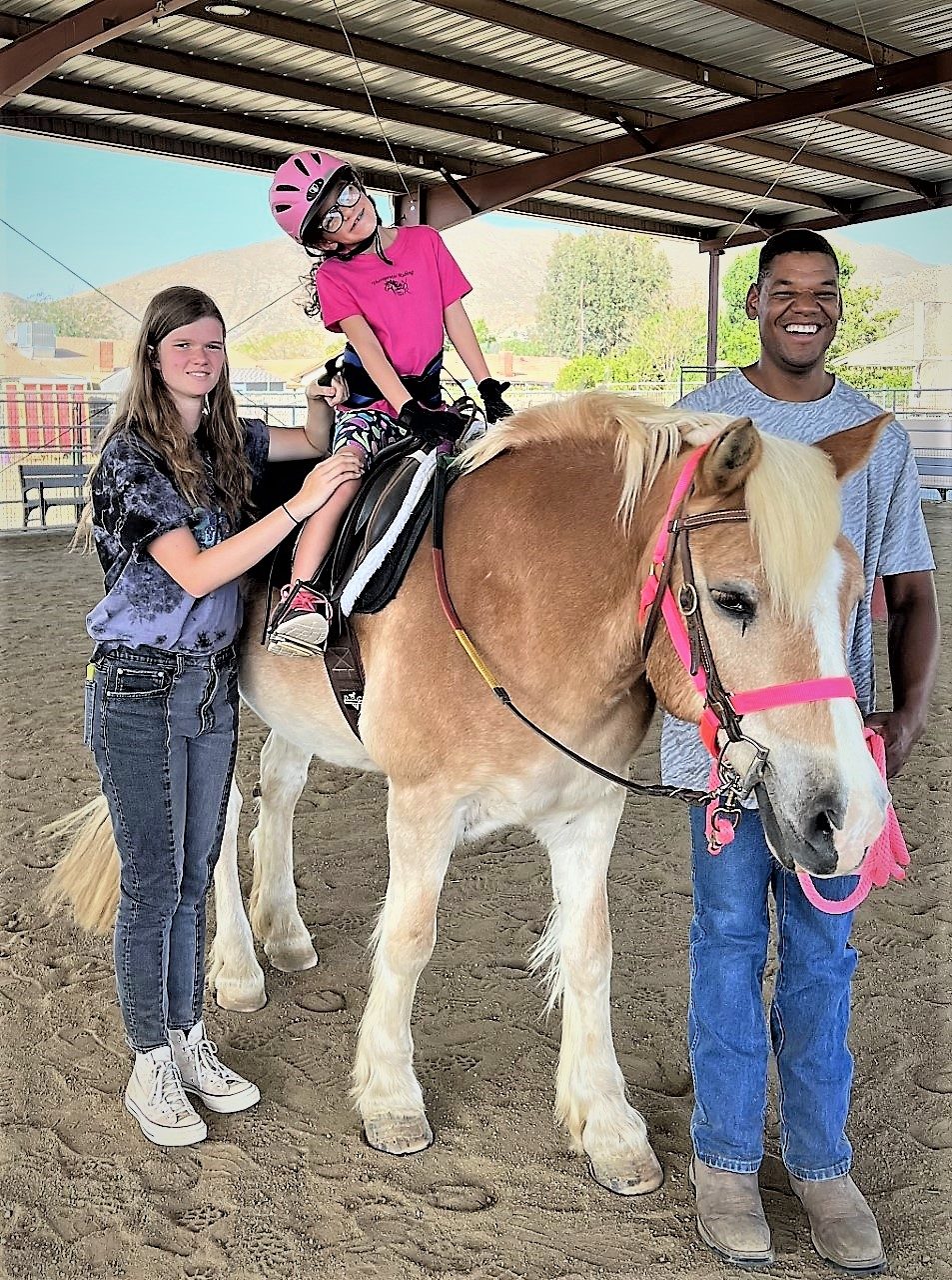 A young rider on a palomino horse flanked by two side-walkers